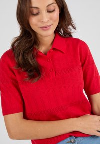 Rode gebreide polo met korte mouwen, voorzien van een gestructureerd patroon, een twee-knops sluiting en ribgebreide kraag en zoom.