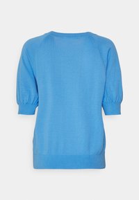 Světle modrý svetr s krátkým rukávem, s upnutým žebrovaným výstřihem a manžetami. Má volný střih s nařasením na rukávech.