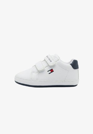 Scarpa da ginnastica bianca per bambino con due cinturini in velcro, rinforzo sul tallone blu navy e un piccolo logo rosso, bianco e blu sul lato.
