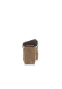 Zapato de cuña de ante marrón con suela blanca, que presenta un ribete trenzado y un acento rosa, visto desde atrás, mostrando un diseño de punta redondeada.