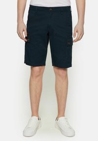 Shorts cargo en coton bleu marine avec poches latérales boutonnées, fermeture à bouton et coupe droite, associés à des baskets blanches.