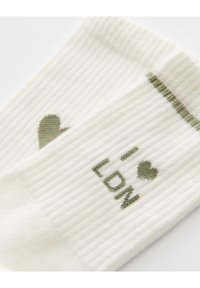 White ribbed socks featuring green heart and "I ❤️ LDN" text. The top has a green accent stripe. Soft texture with distinctive design elements.