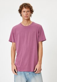 T-shirt a maniche corte, girocollo, in cotone color malva. Presenta una vestibilità morbida e una texture liscia con dettagli di cucitura basic.