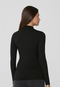 Schwarzes Langarmoberteil aus einem glatten, dehnbaren Stoff. Verfügt über einen hohen Kragen und eine taillierte Silhouette. Rückansicht aufgenommen.