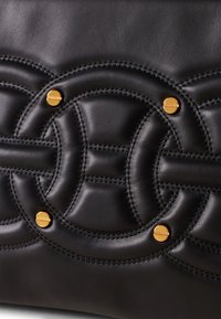 Black leather bag featuring a quilted design, gold hardware accents, and intricate stitched patterns creating a textured surface.