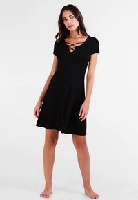 Czarna sukienka z krótkim rękawem o dopasowanym gorsecie i rozszerzanej spódnicy, z ozdobnym dekoltem w kształcie skrzyżowania i gładką fakturą tkaniny.