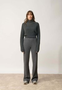 Šedý pletený rolák s dlouhými rukávy, spárovaný s šedými širokými kalhotami. Tento outfit je charakterizován měkkou texturou a jemným žebrováním.