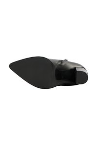 Zwarte leren schoen met een puntige neus, voorzien van een gladde bovenkant, lage blokhak en een geprofileerde zool voor grip. Maat gemarkeerd als 38.