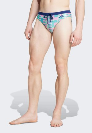 Bañador tipo slip con una cinturilla azul y un patrón gráfico en rosa y verde. Fabricado en una tela elástica, cuenta con un cordón delantero para ajuste.