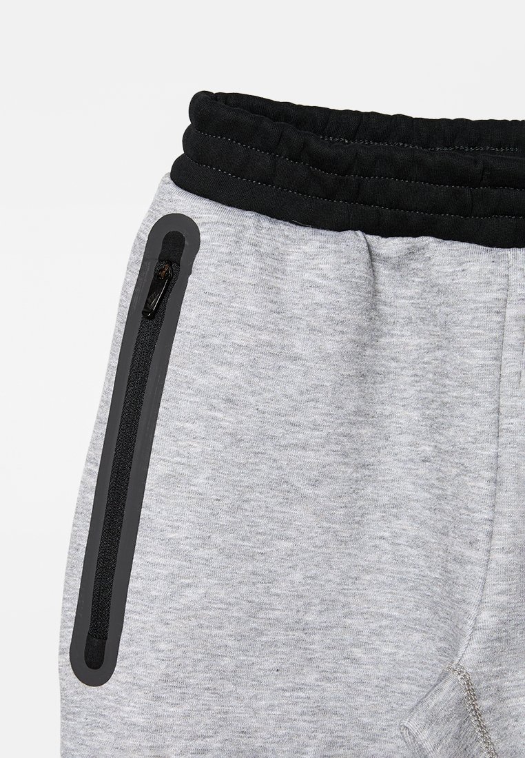 Grijze sweatpants met een zwarte elastische tailleband, zijzak met rits en een gladde textuur met een gemêleerde afwerking.