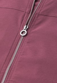 Silver zipper with round pull tab on mauve fabric showing detailed stitching and metal teeth in close-up view.