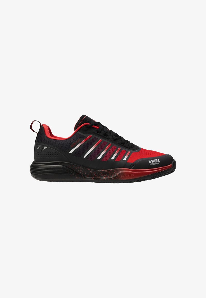 Chaussure de sport noir et rouge avec une tige en maille texturée, des bandes blanches proéminentes et une semelle rouge mouchetée. Dotée d'un design rembourré et d'une languette de traction.