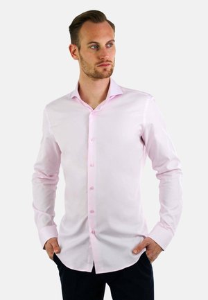 Lichtroze overhemd met lange mouwen en een button-down kraag, gemaakt van soepel materiaal met bijpassende knopen, gecombineerd met donkere broek.