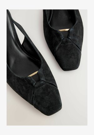 Czarne zamszowe szpilki z noskiem w kształcie ostrym i wycięciami. Posiadają złoty akcent na cholewce oraz gładką, matową teksturę.