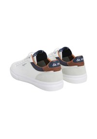White suede sneakers with navy and brown accents, featuring a textured heel and a white rubber outsole. Logo on the side and heel.