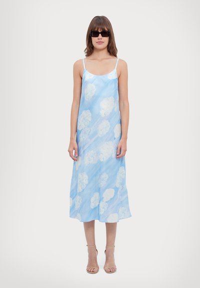 Rochie slip de culoare albastru deschis cu model de nori; realizată dintr-un material neted, are bretele subțiri și ajunge până la jumătatea gambei; asortată cu sandale bej cu curele.