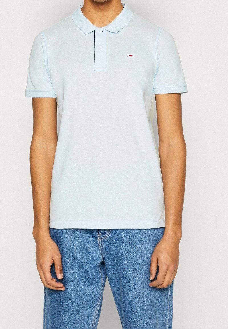 Polo bleu clair avec un col à revers, manches courtes et petit logo sur la poitrine. Fabriqué en coton doux avec une texture lisse.