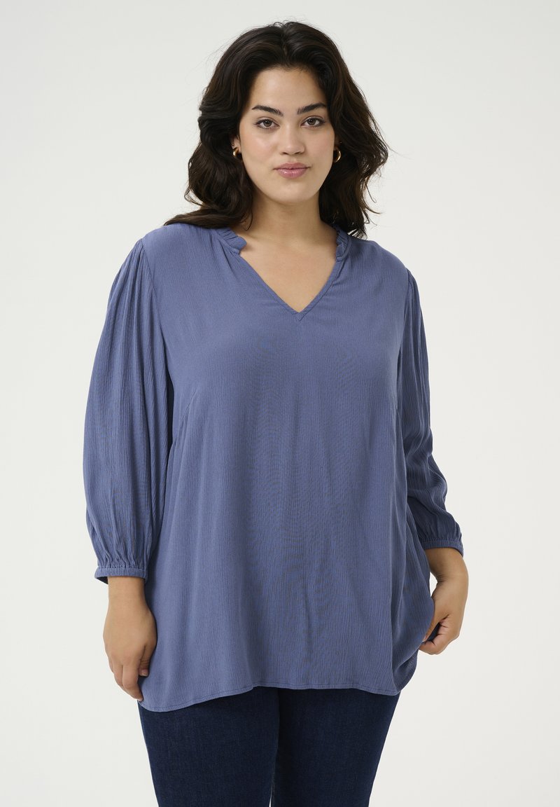 Blusa leggera blu con scollatura a V e maniche a sbuffo arricciate. Presenta una vestibilità comoda e sottili righe verticali sul tessuto.
