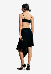 Mustast topist ja allosast koosnev komplekt, kus on seljas hästi istuv rihmadeta topp ja voolav asümmeetriline seelik, täiustatud mustade kõrgete kontsadega kingadega.