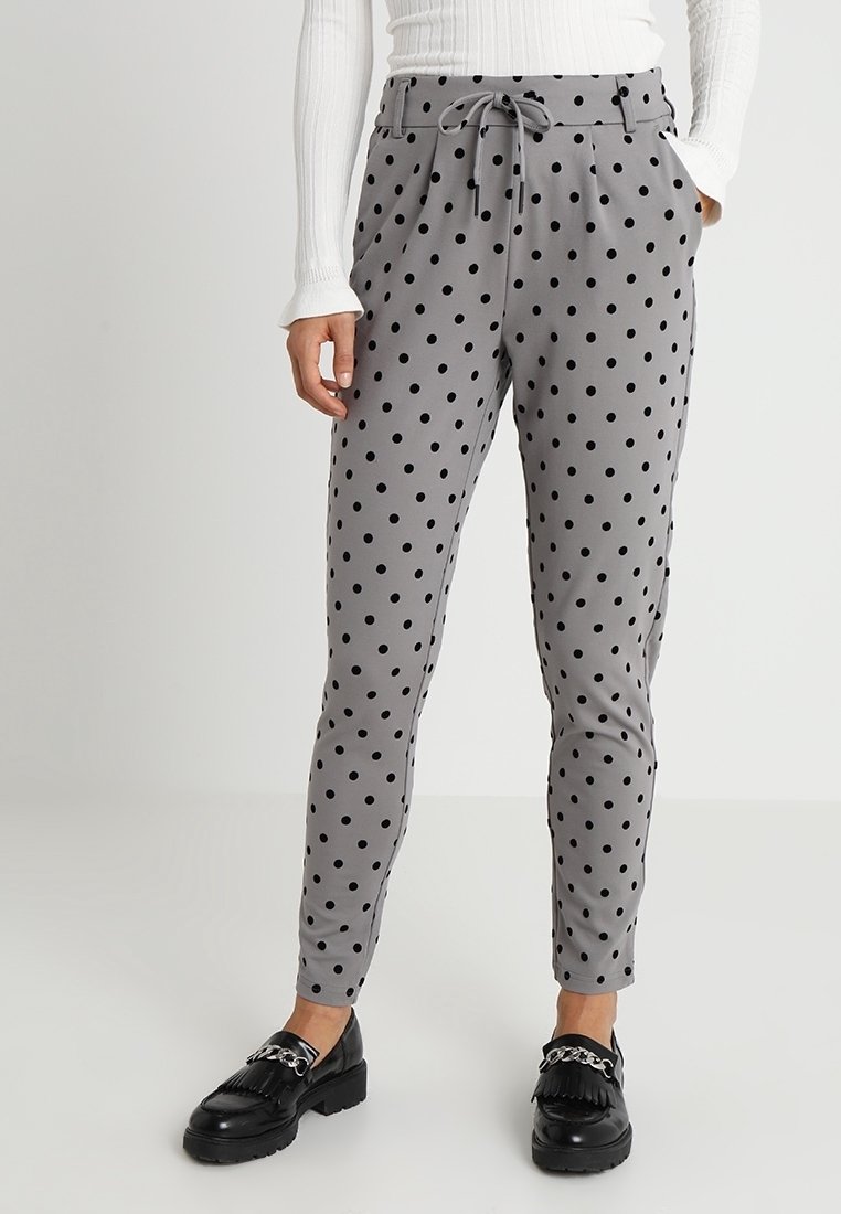 Grijze broek met stippen, voorzien van een trekkoord in de taille en een taps toelopende pasvorm, gecombineerd met zwarte instappers. Soepele stof met een lichte glans.