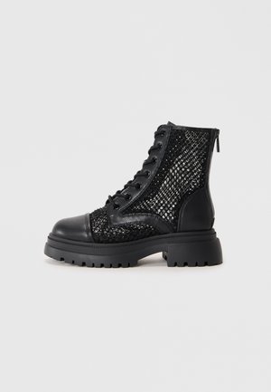 Black ankle boots featuring a textured mesh upper with sequins, leather cap toe, and a chunky rubber sole. Side zip closure for easy wear.