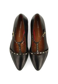 Sandales à talons en cuir noir avec une bride T, bout pointu, ornées d'accents en studs dorés le long de la bride et d'une doublure intérieure rouge.