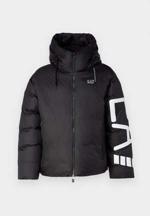 Crna puffer jakna s visokim ovratnikom, prednjim zatvaračem i oversized kapuljačom. Ima bijeli logotip na lijevoj ruci i kviltanu teksturu.