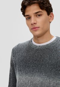 Szary i czarny sweter w paski z prążkowaną fakturą. Posiada okrągły dekolt i długie rękawy, uszyty z miękkiego materiału.