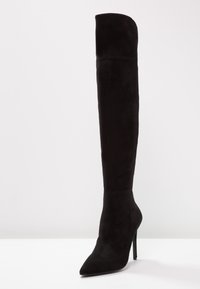 Black suede over-the-knee stiletto boot with a pointed toe and smooth texture. Slim, high heel and fitted silhouette.