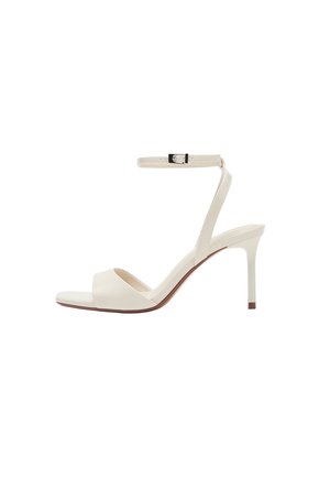 Cremefarbene High-Heel-Sandale mit schmalem Knöchelriemen und Schnalle, offenem Zeh und Stöckelabsatz, vor weißem Hintergrund dargestellt.