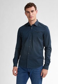 Camicia abbottonata blu scuro con pois bianchi, maniche lunghe e taschino sul lato sinistro del petto; tessuto liscio con colletto semplice.