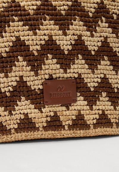 Tkanona slamnata torba z rjavimi in bež vzorci ter rjavim usnjenim značko, na katerem je vžigano logotip "MISSONI".