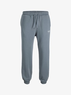 Pantaloni joggers grigio chiaro realizzati in morbido tessuto, dotati di vita elasticizzata con coulisse regolabile e polsini arricciati. Dettaglio del logo piccolo sul lato.