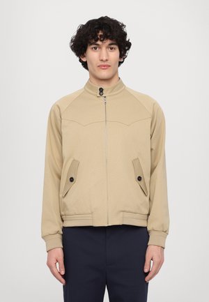 Beige zip-up jacket with a stand collar, side pockets, and ribbed cuffs. Features stitched detailing and a fitted silhouette.