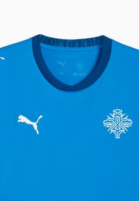 Μπλε αθλητικό μπλουζάκι με στρογγυλή λαιμόκοψη και λευκά κεντημένα λογότυπα: Puma στα αριστερά και γεωμετρικό σχέδιο νιφάδας στο κέντρο.