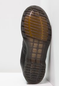 Suola in gomma nera con superficie testurizzata, caratterizzata da un motivo a griglia e scanalature sollevate per migliorare la presa. Tacco curvato per il comfort.