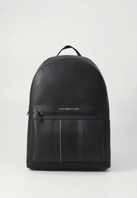 Musta nahkainen reppu, jossa pyöreä yläosa, vetoketjullinen etutasku ja teksturoitu raitadetalji. Edessä logo. Säädettävät olkahihnat.