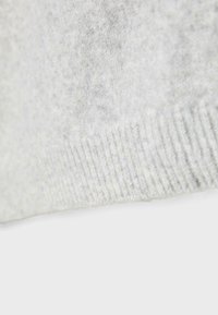 Hellgrauer Strickstoff mit weicher Textur, der einen gerippten Saum und eine glatte Oberfläche aufweist und leichte Farbvariationen zeigt.