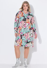 Bunt gemustertes Kleid mit langen Ärmeln, V-Ausschnitt und Druck von stilisierten Gesichtern und Herzen; der Stoff wirkt weich, glatt und farbenfroh.