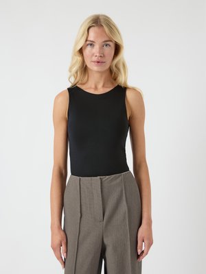 Black sleeveless bodysuit with a round neck, paired with high-waisted, gray, textured pants featuring front pleats.