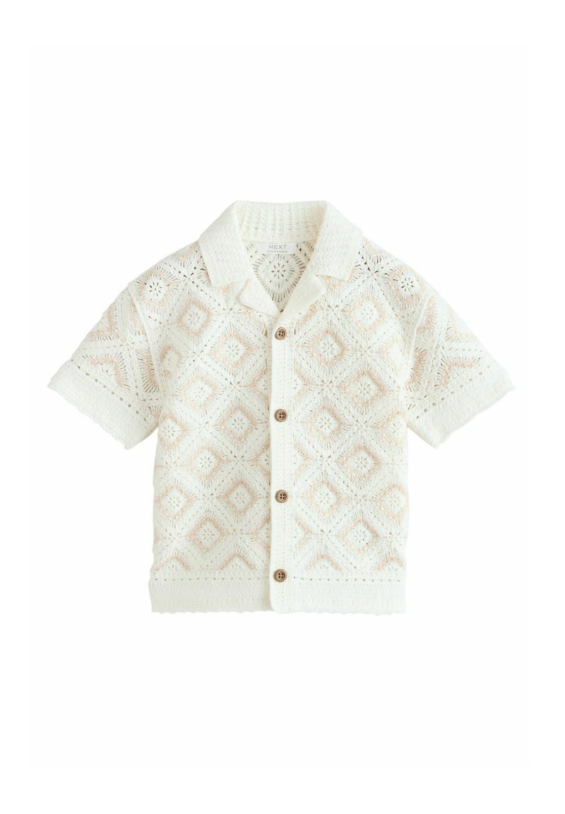 Lyhythihainen valkoinen virkatumpi paita timanttikuvioilla, jossa on kauluksellinen pääntie ja puiset napit kiinnityksessä. Pinnan rakenne on pitsimäinen.