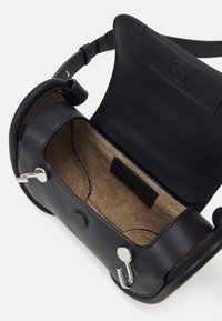 Borsa a tracolla in pelle nera con interni foderati in suede, dotata di hardware in argento, chiusura a scatto magnetico e tracolla regolabile.