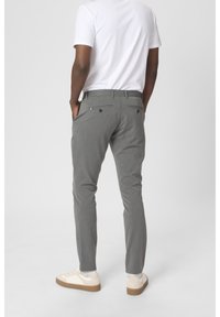 Šedé, přizpůsobené kalhoty s hladkou strukturou a Slim Fit. Obsahují klasické kapsy a jemné vzory, doplněné o bílé tenisky.