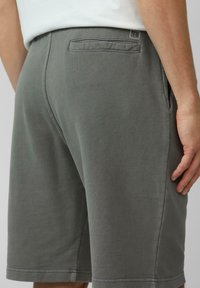 Grijze katoenen shorts met een achterzak, uitgerust met een gladde textuur en een rechte snit. Eenvoudige stiksels rond de zoom. Merklogo zichtbaar.
