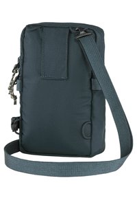Borsa compatta di un verde scuro con un esterno in nylon testurizzato, tracolla regolabile e punti di attacco laterali per accessori. Chiusura semplice a zip e patch sul retro.