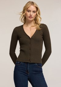 Olivgrön ribbad kofta med V-ringning, åtsittande långärmar och bruna knappar framtill, tillverkad av ett mjukt, texturerat stickat material.