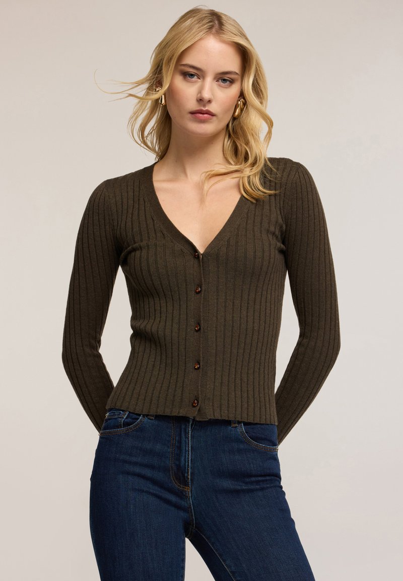 Olivgrön ribbad kofta med V-ringning, åtsittande långärmar och bruna knappar framtill, tillverkad av ett mjukt, texturerat stickat material.