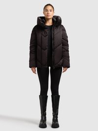 Must must pufferjakk suurte kapuutsiga, teemantmustriga tikand, ees tõmblukk ja pikad varrukad, kombineeritud mustade retuuside ja põlveni ulatuvate saapadega.