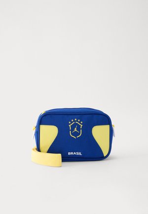 Kompakt kék testre vethető táska sárga díszítéssel, sárga pánttal és az alatta lévő, öt csillagos címer alatt nyomtatott „Brasil” felirattal.