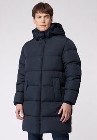 Marine blauwe pufferjas met een capuchon, voorzien van een gestikte design, voordezakken en een hoge kraag. Gemaakt van soepel, lichtgewicht materiaal.